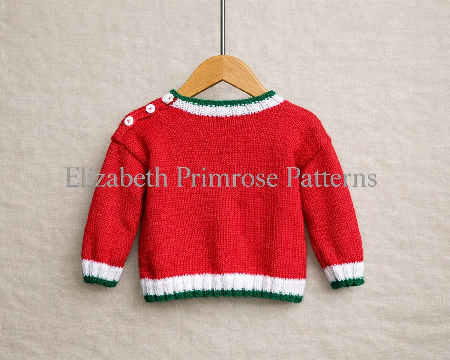 Back view of red children’s knitted jumper on a wooden hanger with green and white trims and shoulder buttons against a smooth beige fabric background.