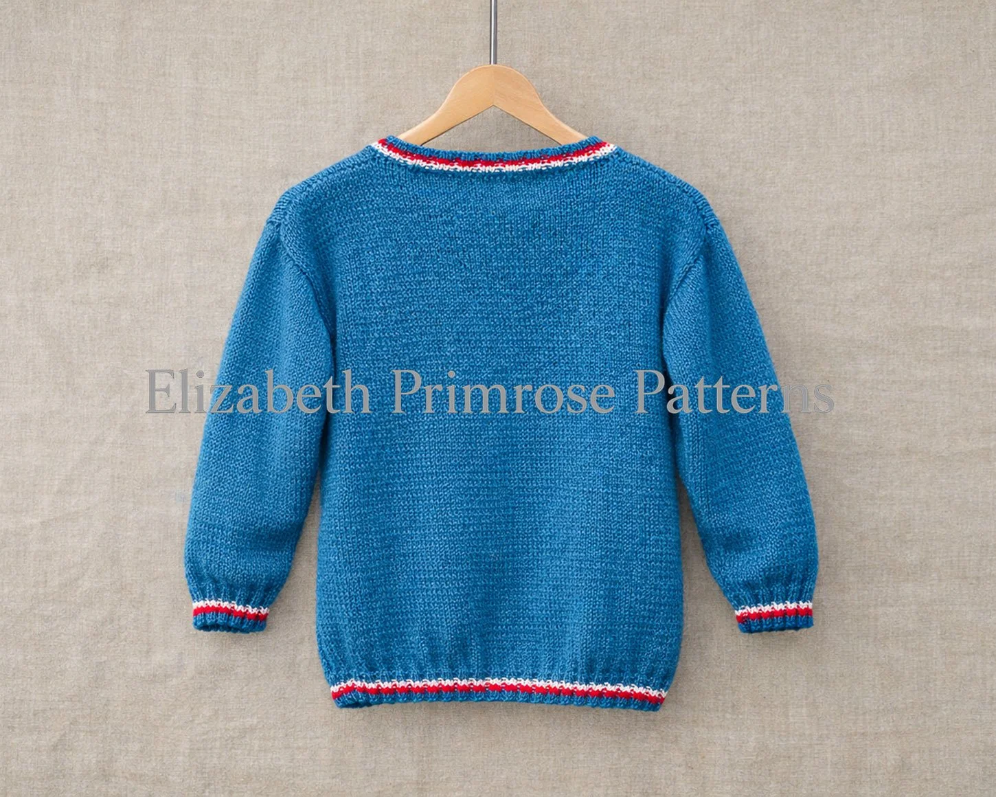 Back view of a blue knitted children’s jumper with striped neckline, cuffs, and hem, hanging on a wooden hanger against a beige linen background.