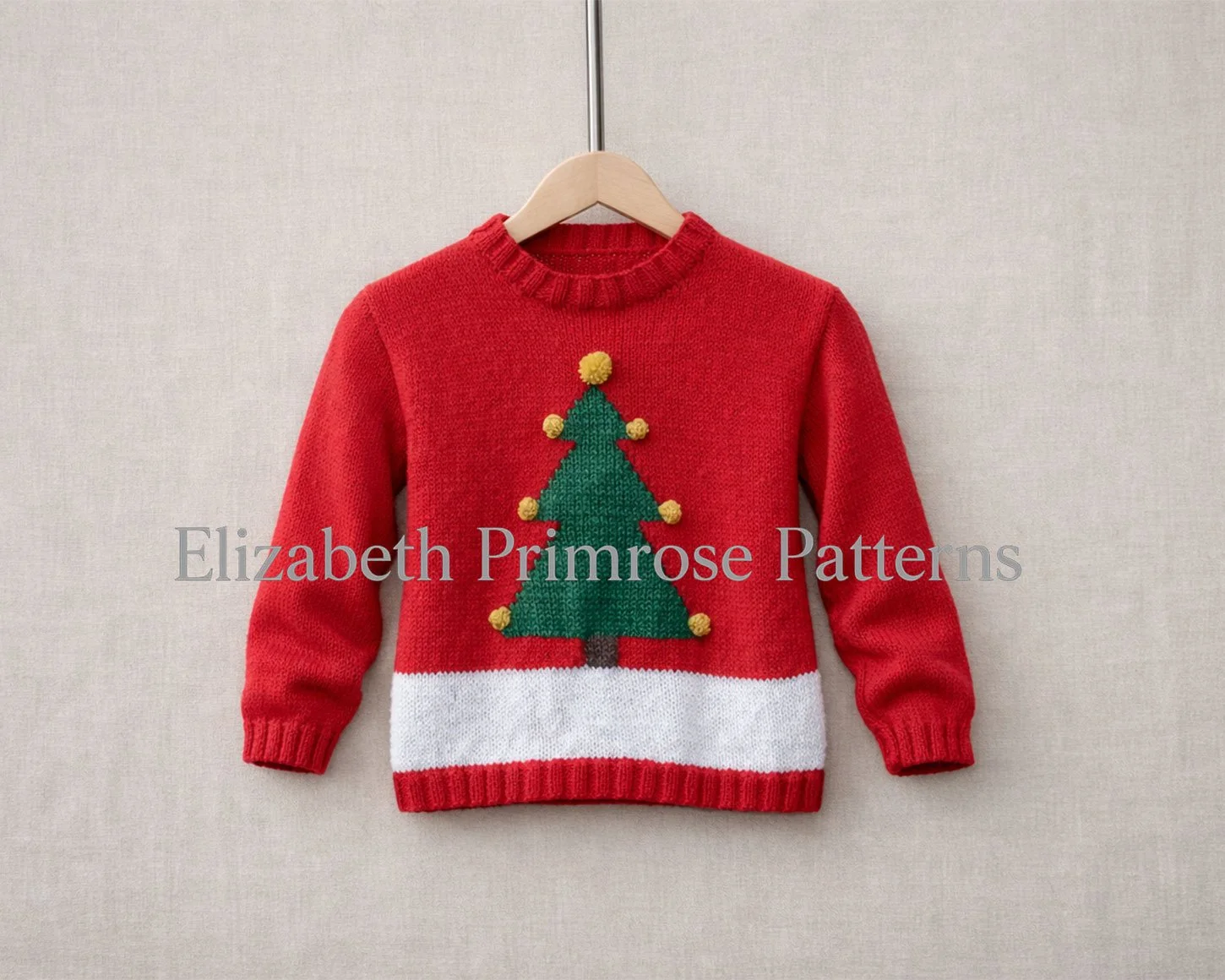 Red children’s Christmas jumper with a green tree and yellow baubles hanging on a wooden hanger against a soft neutral background.