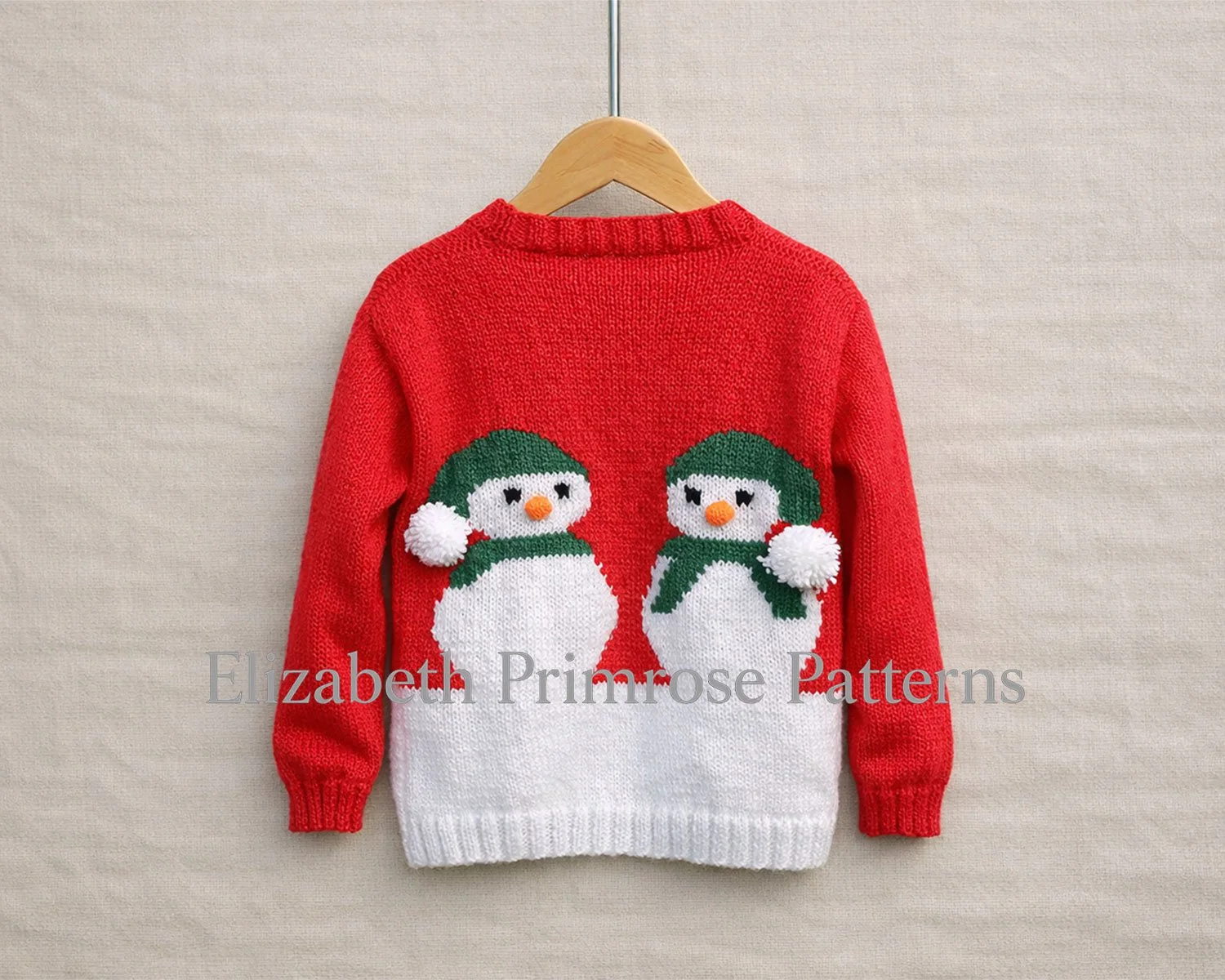 Red children’s jumper shown from the back on a wooden hanger against a smooth beige linen background.