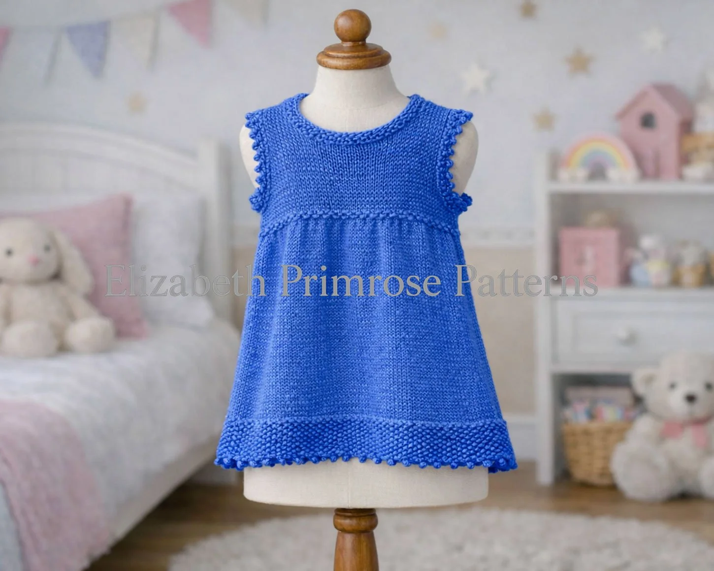 Cornflower blue knitted dress with picot edges shown on a mannequin in a warm, pastel children’s room.