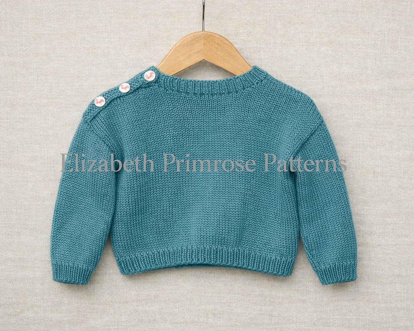 Back of teal children’s Christmas jumper with ribbed neckline and three buttons on the shoulder, displayed on a wooden hanger against soft linen.