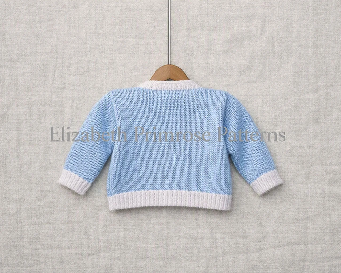 Back view of blue knitted cardigan with white rib edgings on a linen background.