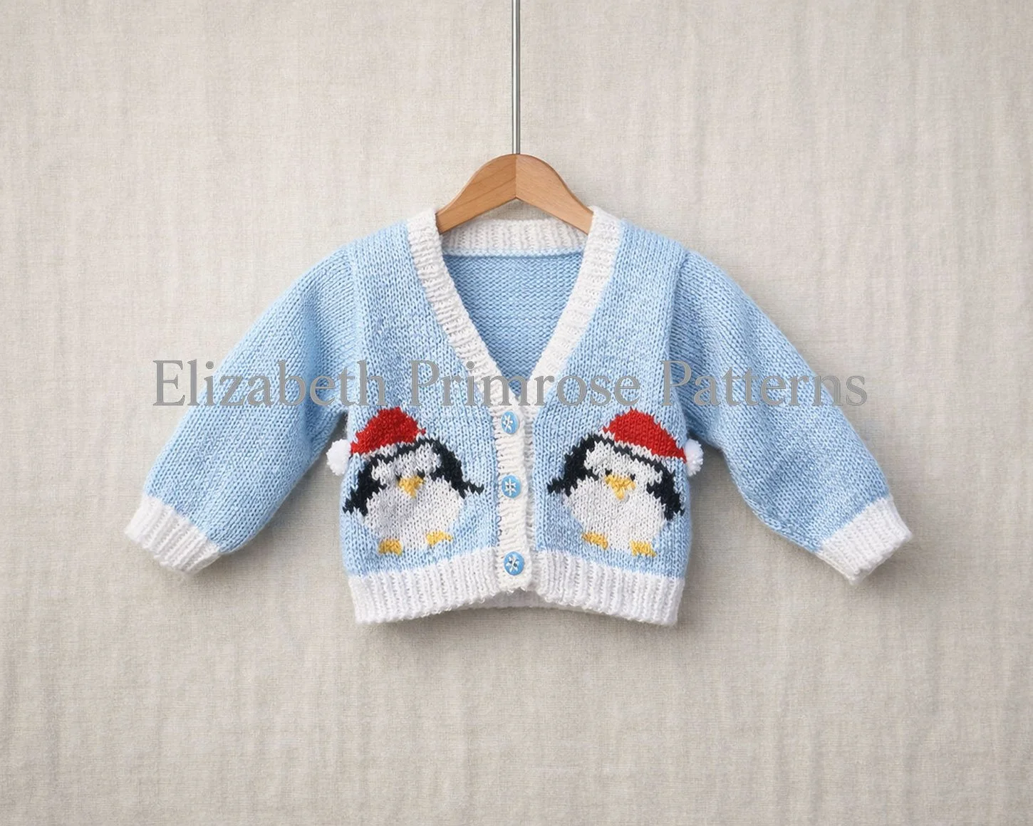 Light blue baby V-Neck cardigan on a wooden hanger with two penguins in Santa hats against a soft beige linen background.