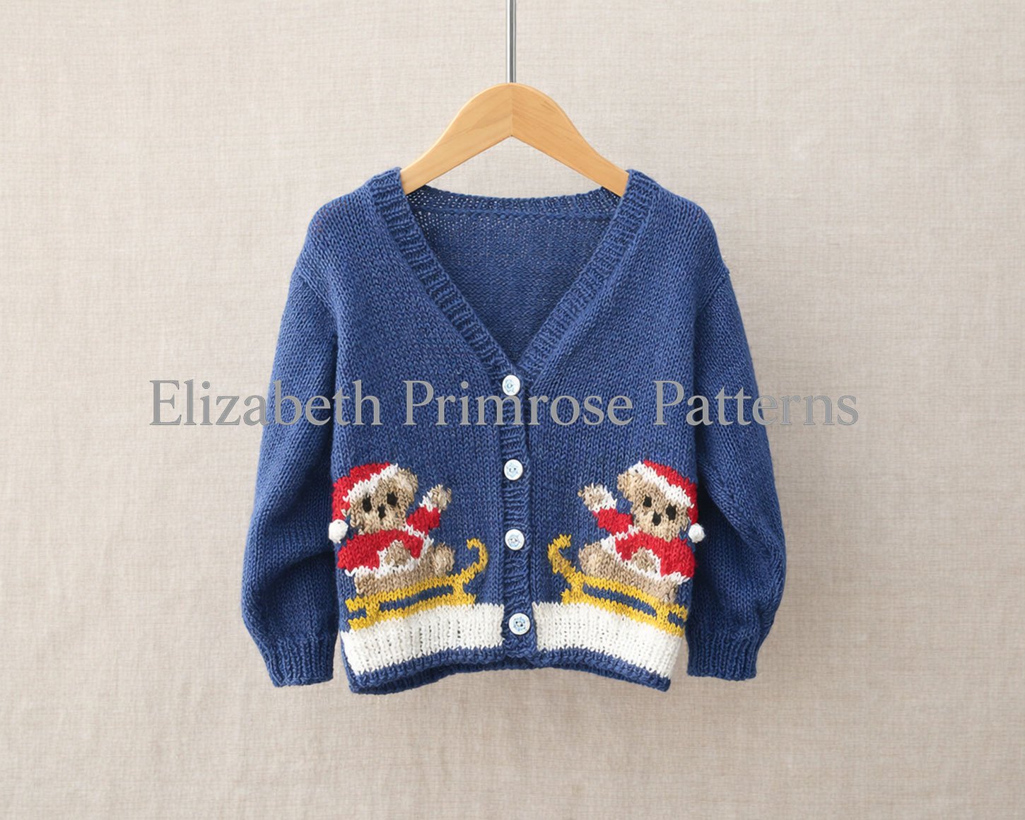 Festive blue v-neck cardigan featuring two teddy on sleigh motifs, shown on a wooden hanger with a neutral fabric backdrop.