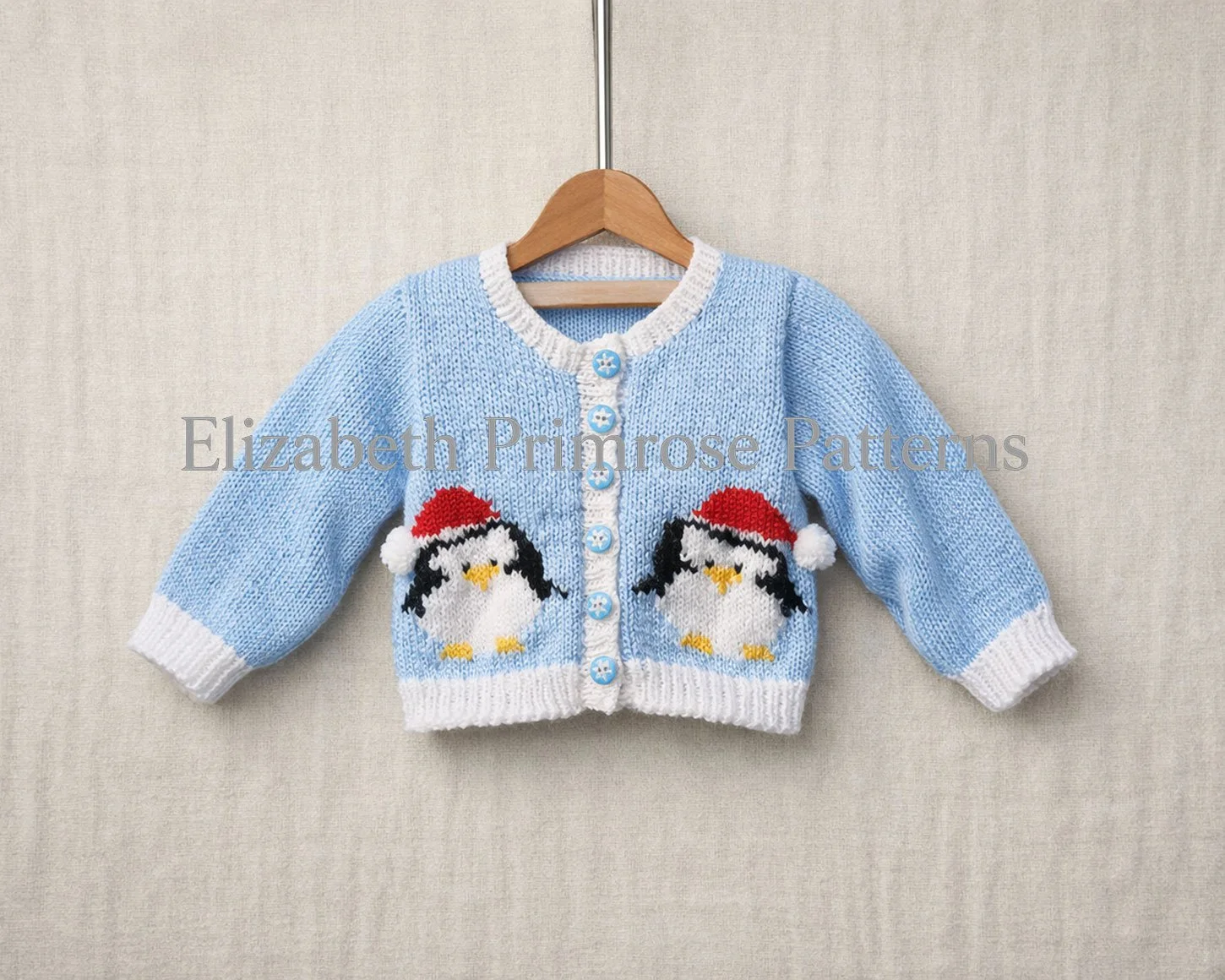 Light blue baby Round Neck cardigan on a wooden hanger with two penguins in Santa hats against a linen background.