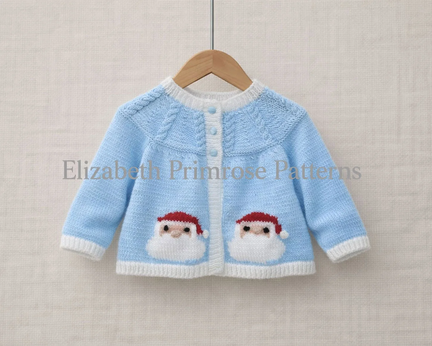 Light blue baby cardigan with Santa motifs hanging on a wooden hanger against a soft beige fabric background.