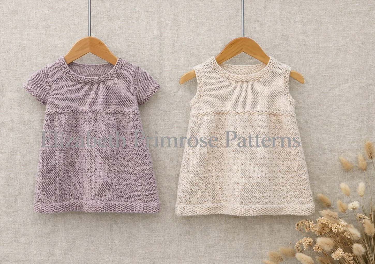 Soft lavender and cream knitted Dewdrop Dresses displayed on hangers with a linen background and muted flowers in one corner.