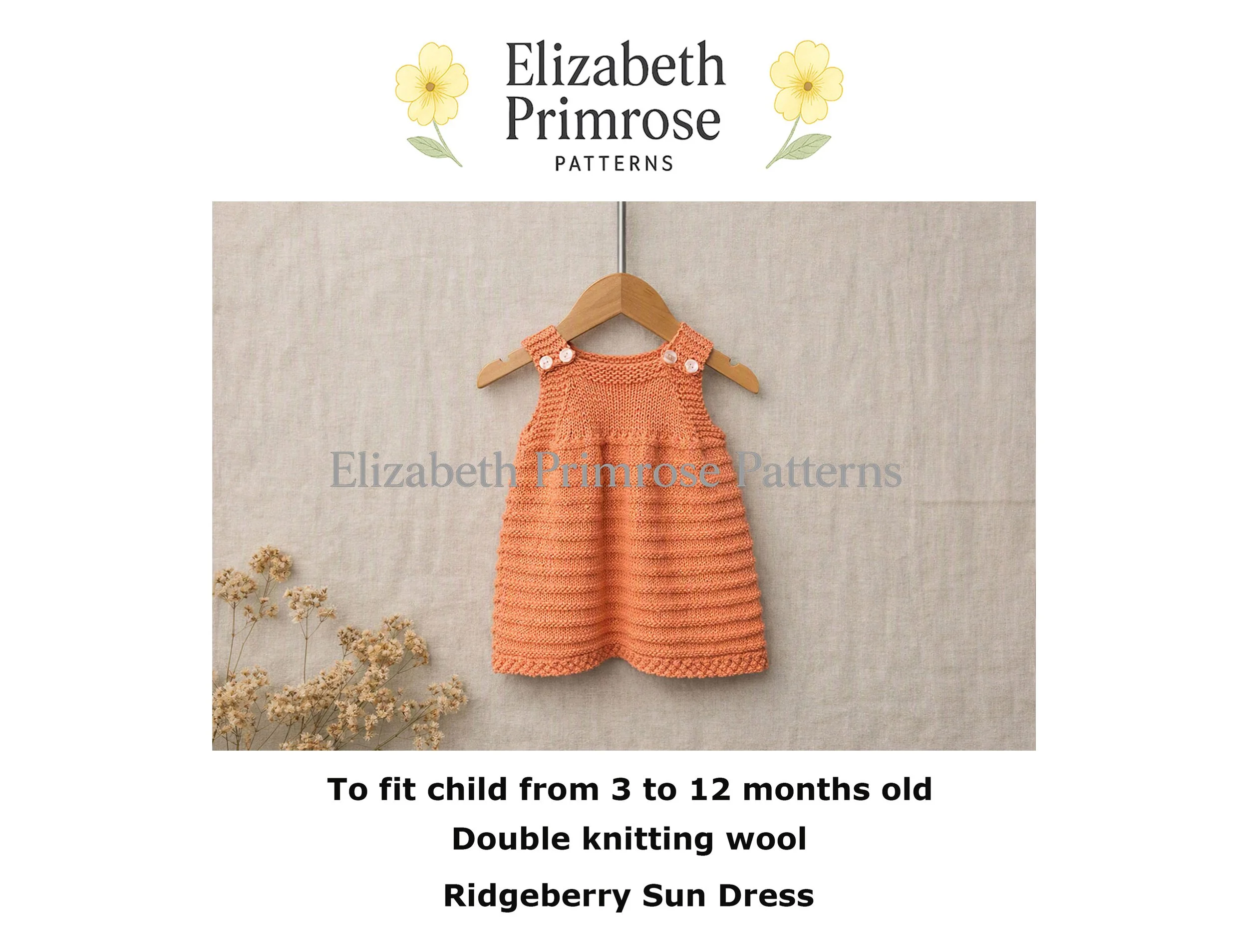 Peach knitted baby dress with buttoned straps hanging on a wooden hanger against a linen background with dried flowers.