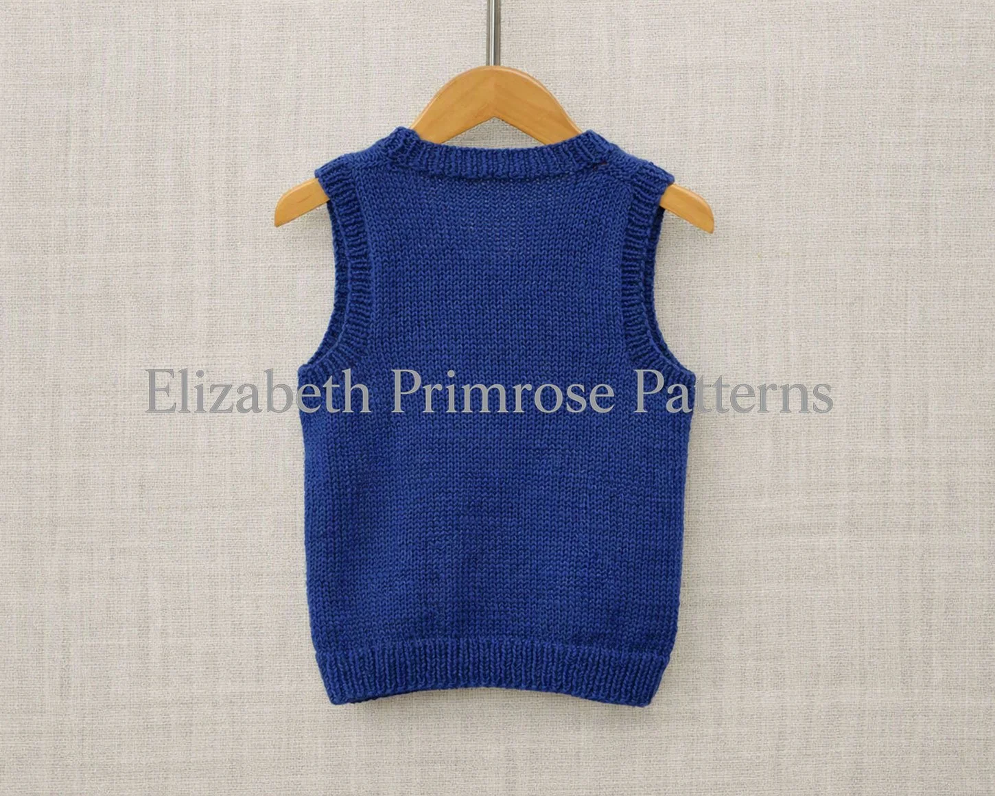 Back view of hand knitted, navy tank top displayed on a hanger against a beige background.