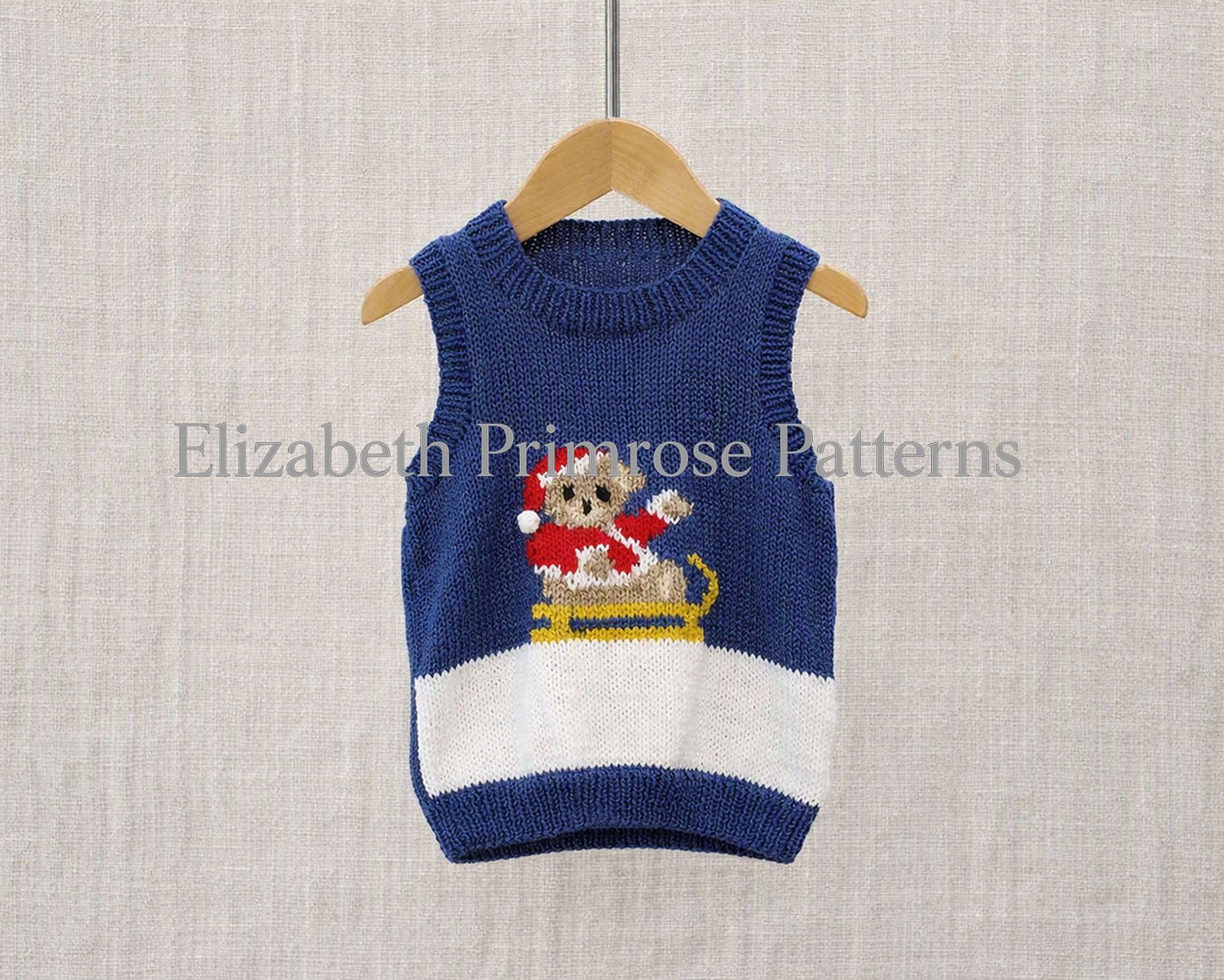 Blue children’s V-neck Christmas vest with teddy bear on sleigh, hanging on wooden hanger against beige textured background.