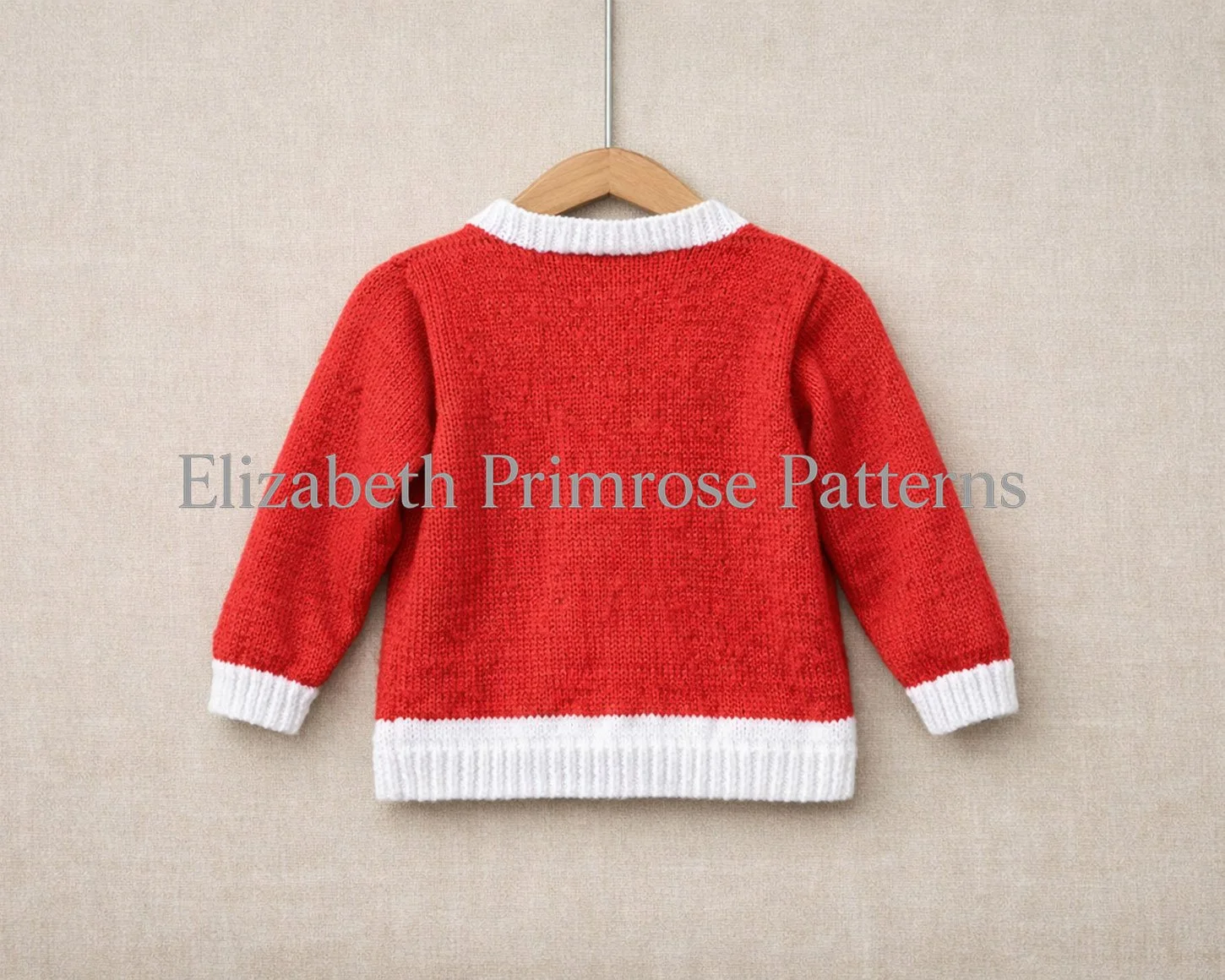 Red children’s cardigan shown from the back on a wooden hanger against a beige linen background, featuring white trims and soft knitted texture.