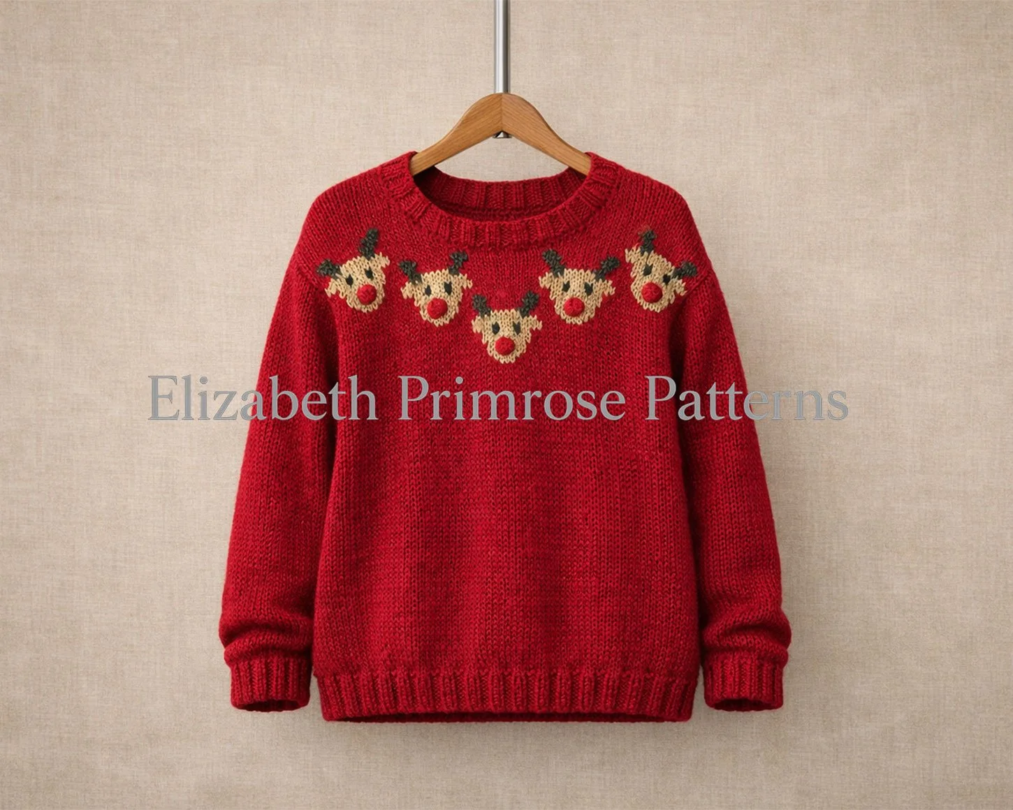 Red children’s jumper on a wooden hanger with five Rudolph faces across the chest, shown against a soft beige linen background.