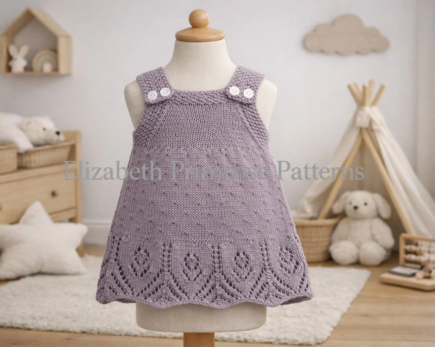 Children’s lavender pinafore dress displayed on a mannequin, showing delicate dot texture, lace hem detail and buttoned straps in a warm, neutral nursery scene.