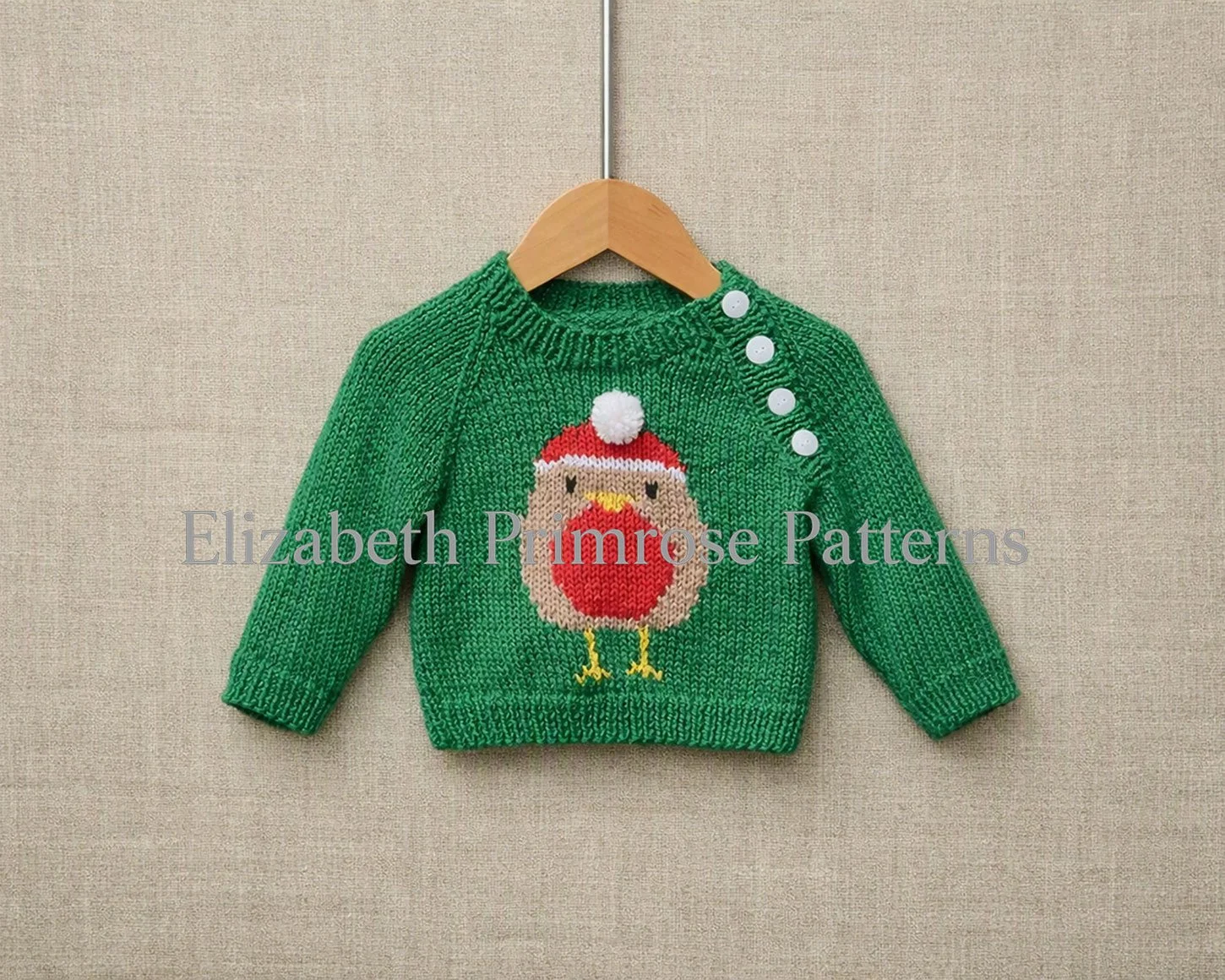 Knitted green children’s jumper featuring a festive robin motif with raglan sleeves and front buttons, displayed on a hanger against a soft beige backdrop.