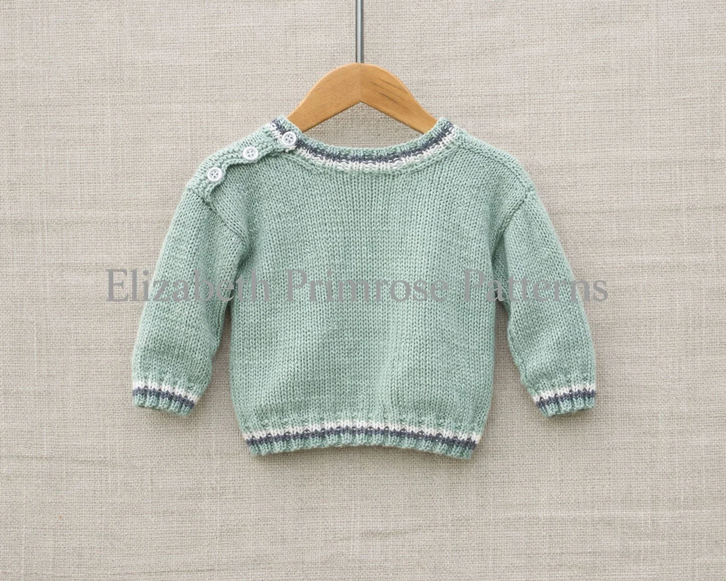 Back view of knitted baby sweater in sage green with grey and white trim, displayed on wooden hanger.