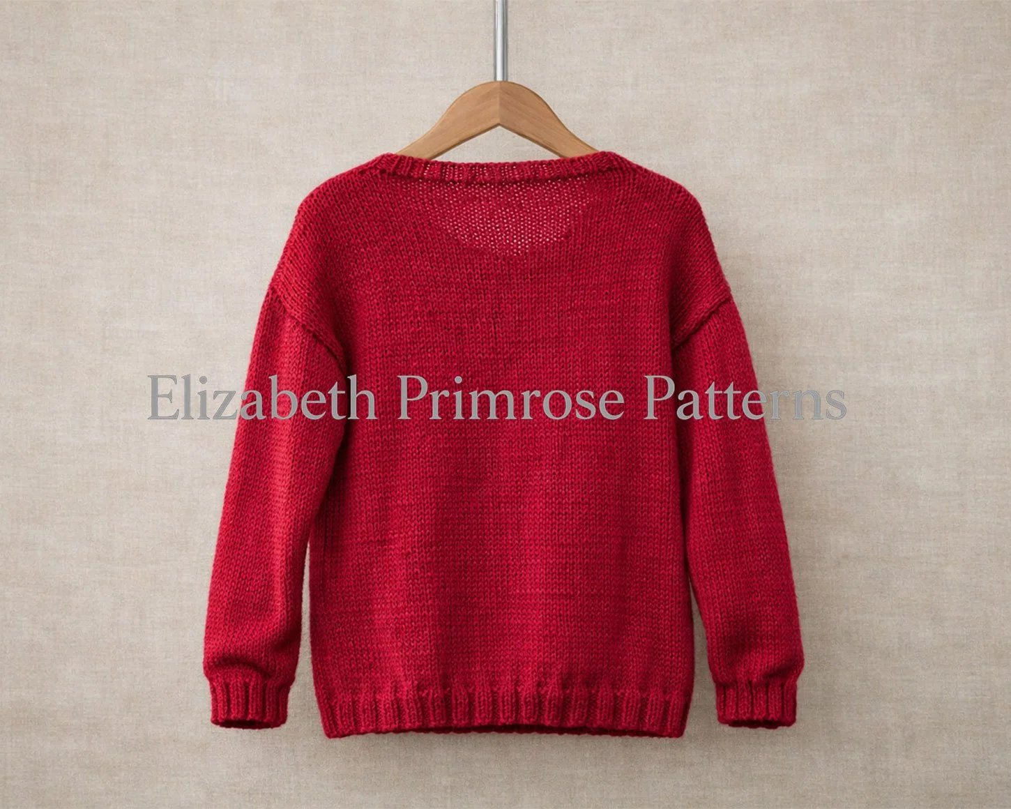 Back view of a red knitted children’s jumper on a wooden hanger, displayed against a neutral fabric backdrop with simple ribbed edges.