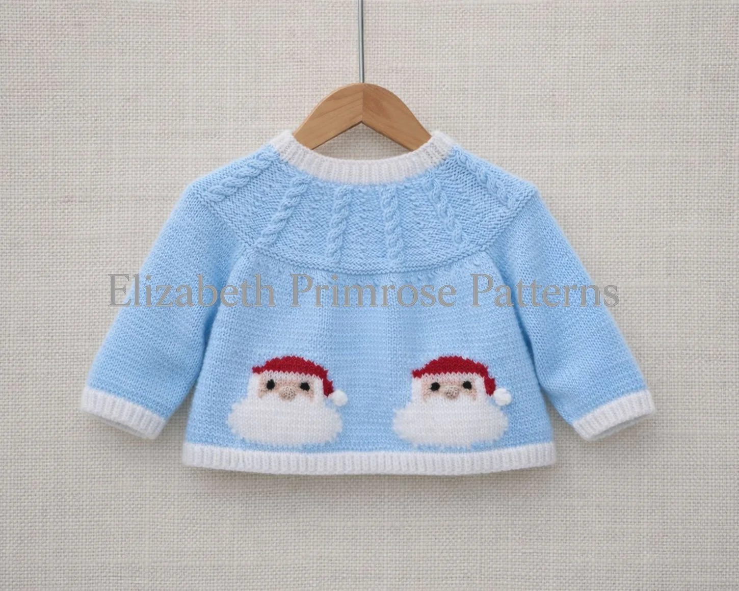 Light blue baby jacket with relaxed sleeves and two Santa motifs on the back, hanging on a wooden hanger against a neutral background.