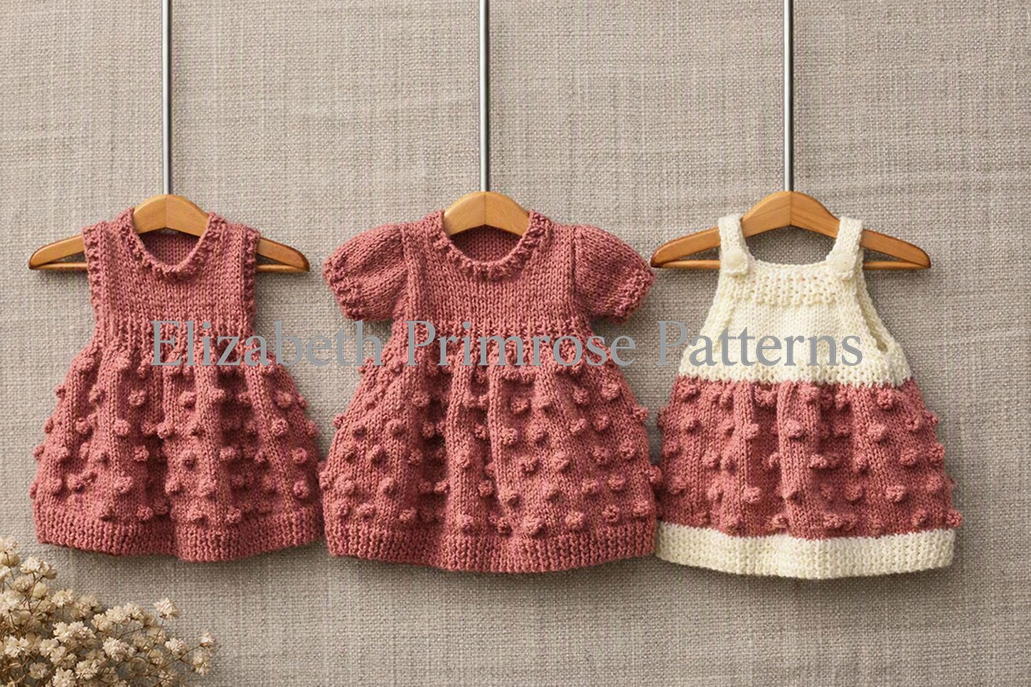 Three hand-knitted pink and cream doll dresses featuring heavily textured bobble stitch skirts on tiny hangers.