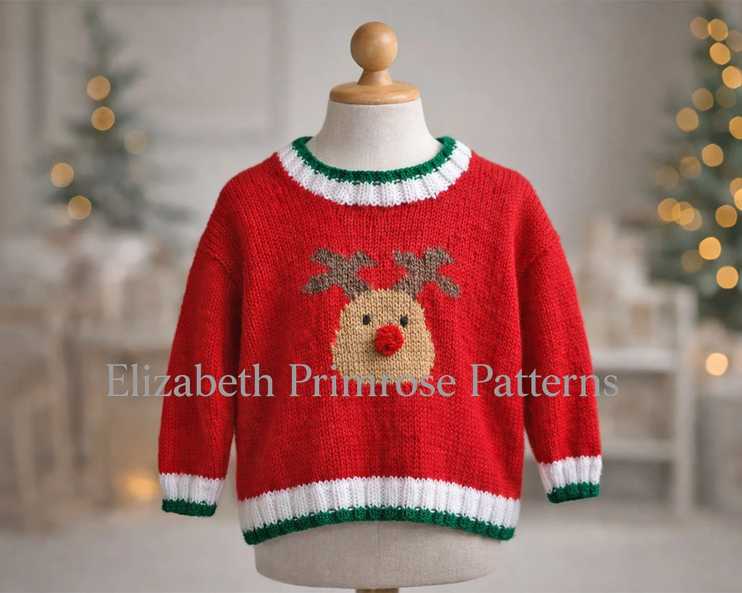 Red knitted reindeer jumper displayed on a mannequin with green and white accents against a warm, softly lit Christmas scene.