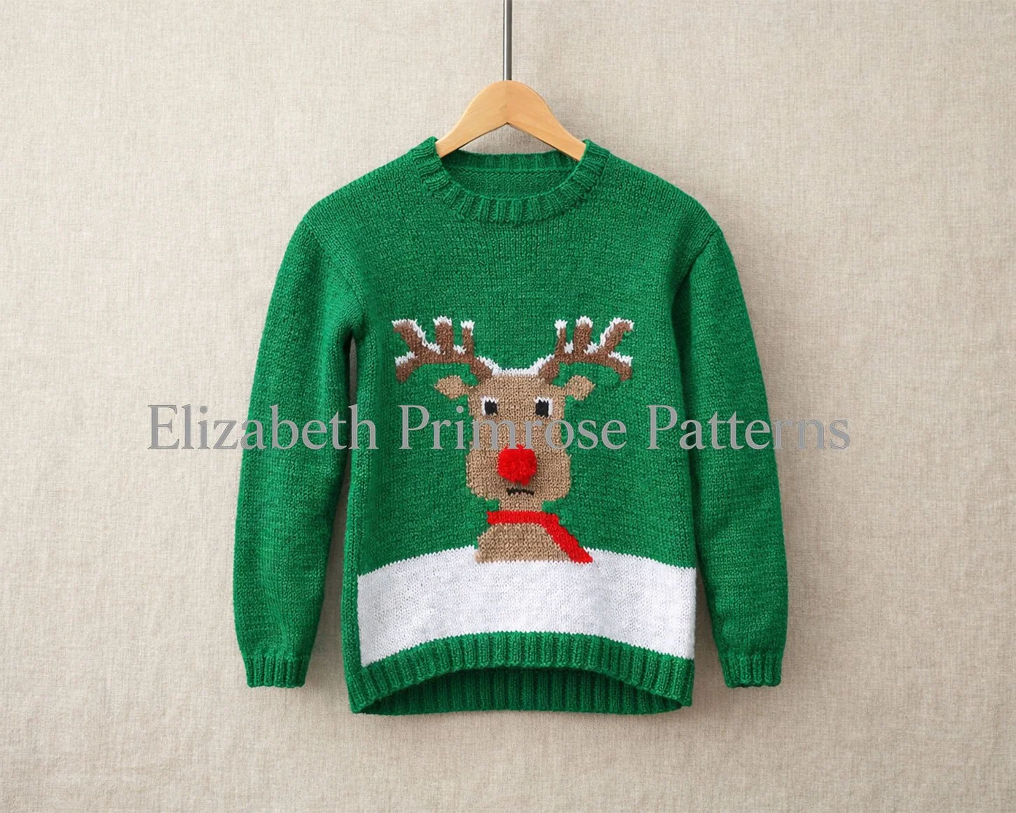 Green knitted Christmas jumper on a wooden hanger, featuring a reindeer with red nose and scarf against an off white linen background.