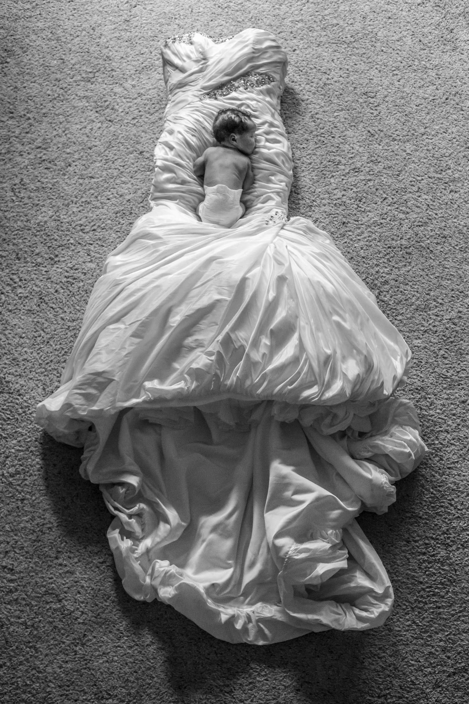 Black and white photo of baby sleeping on wedding dress