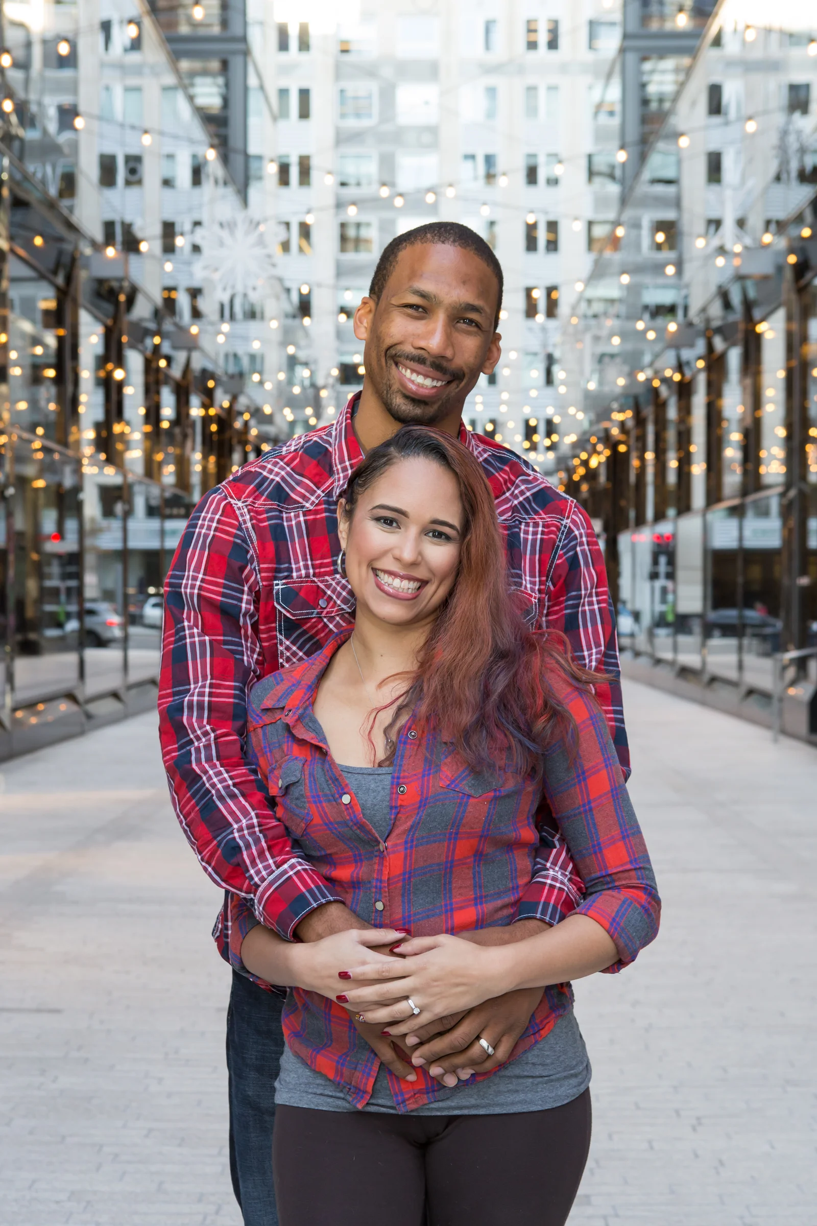 Couple wearing plaid shirts embracing while looking at the camera