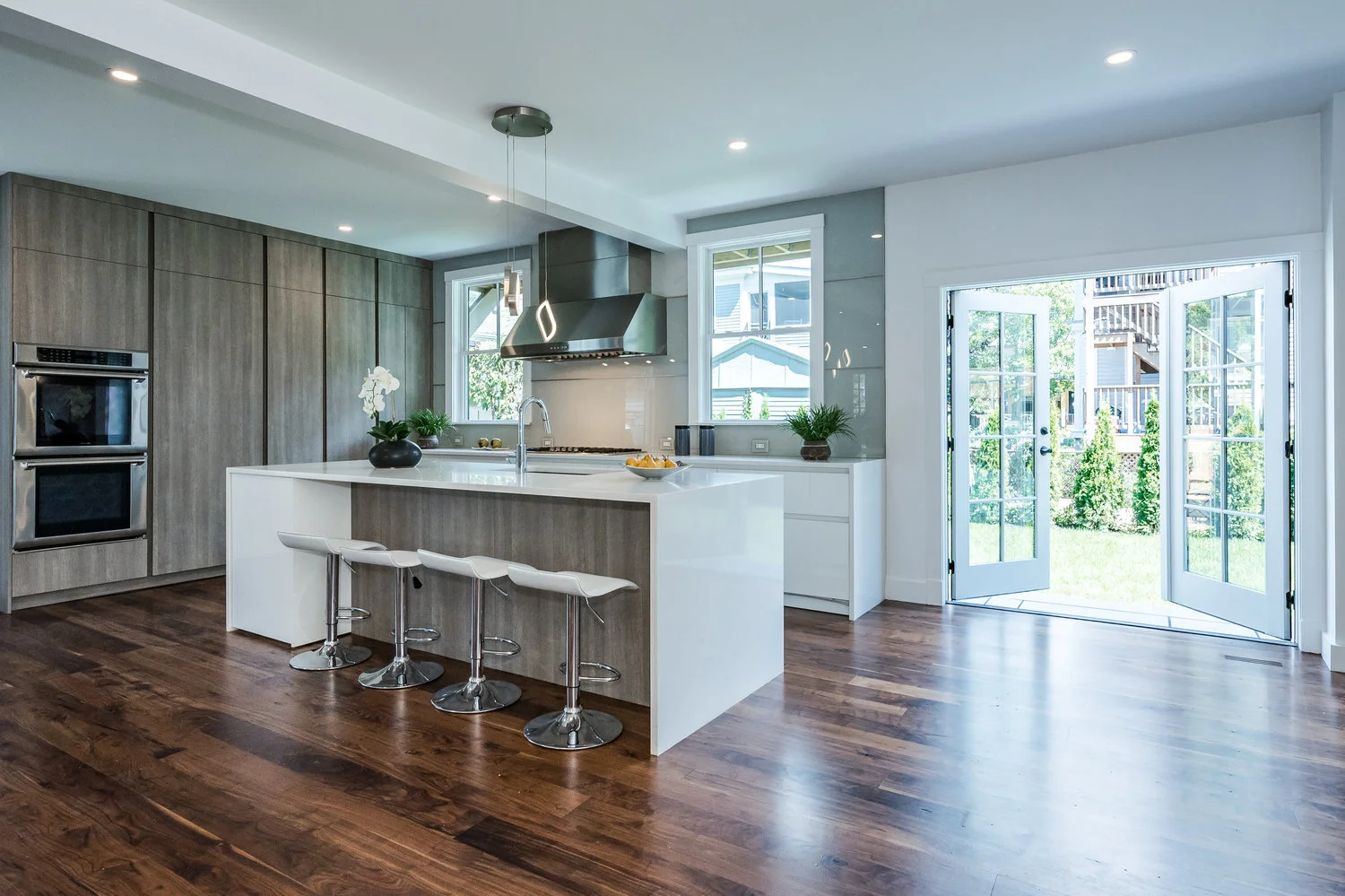 Modern Leicht kitchen with combination white high gloss and oak flat panel cabinets and glass backsplash, dark hardwood floors