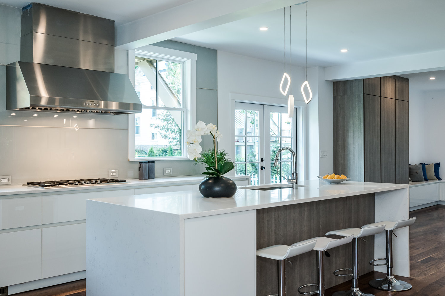 Modern Leicht kitchen with combination white high gloss and oak flat panel cabinets and glass backsplash, dark hardwood floors
