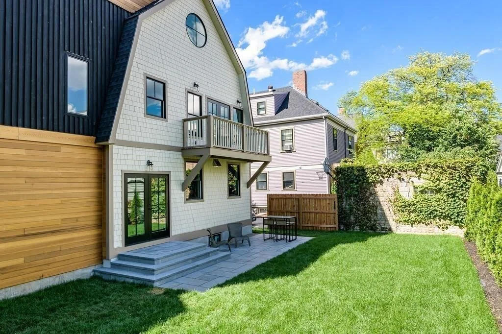 black mansard roof, medium hardwood entry way, windows with black frames, dutch colonial home with modern style improvements in Brookline, Massachusetts