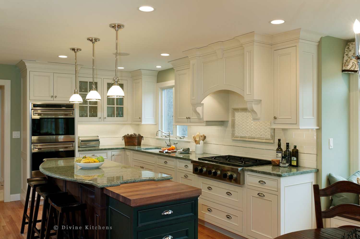 Traditional Kitchen with white shaker cabinetry and double decker appliances. Marble countertops float above a kitchen island and medium hardwood floors. A laundry room is adjacent to the kitchen.