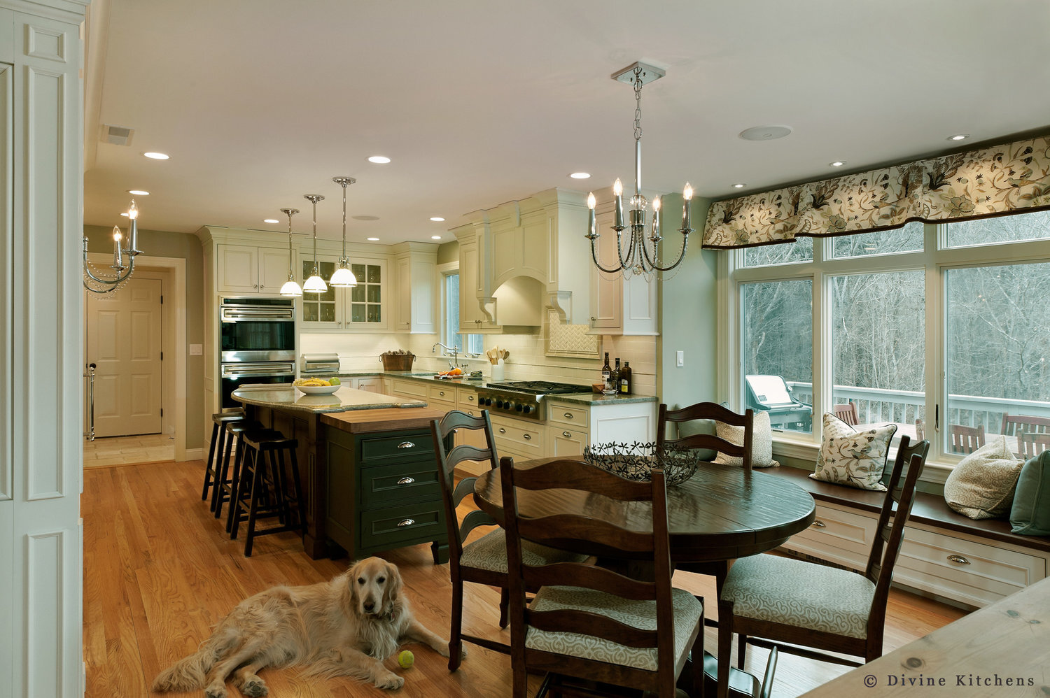 Traditional Kitchen with white shaker cabinetry and double decker appliances. Marble countertops float above a kitchen island and medium hardwood floors. A laundry room is adjacent to the kitchen.