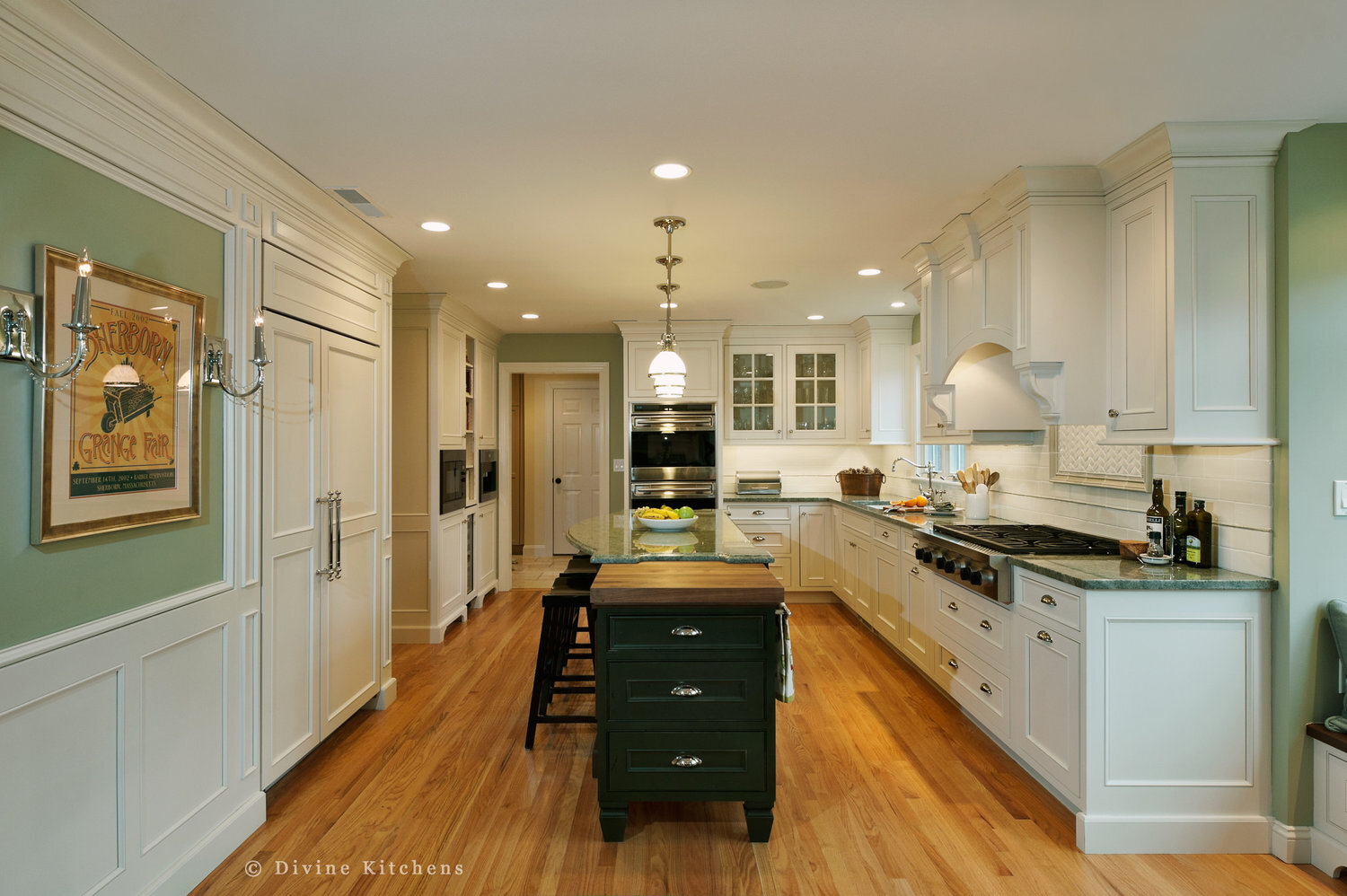 Traditional Kitchen with white shaker cabinetry and double decker appliances. Marble countertops float above a kitchen island and medium hardwood floors. A laundry room is adjacent to the kitchen.