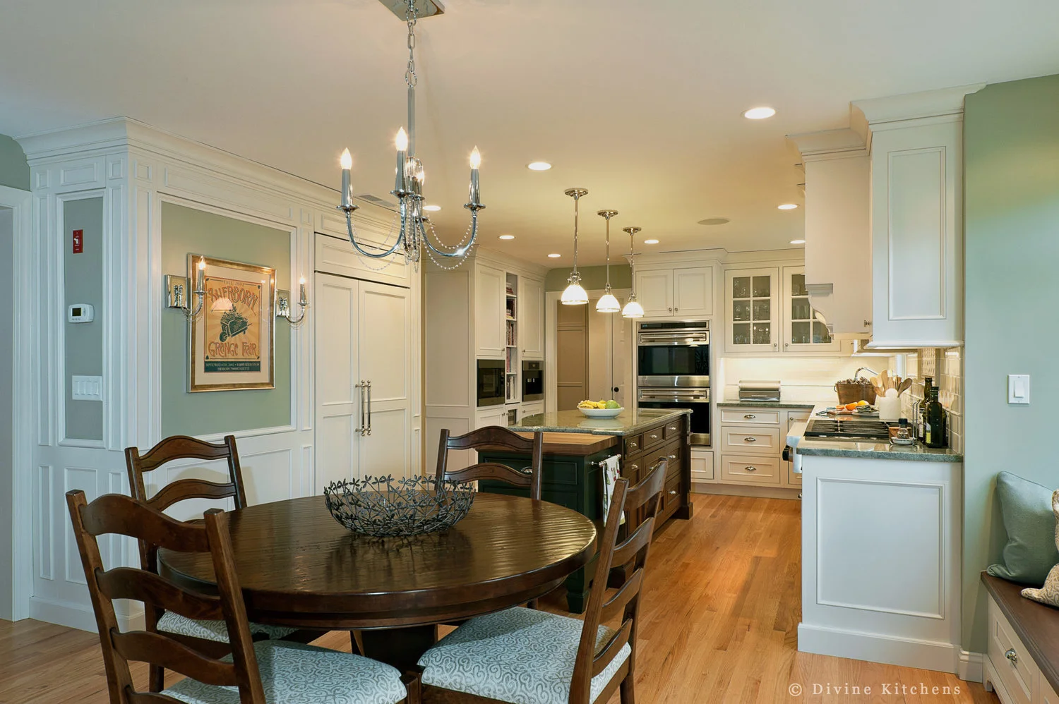 Traditional Kitchen with white shaker cabinetry and double decker appliances. Marble countertops float above a kitchen island and medium hardwood floors. A laundry room is adjacent to the kitchen.