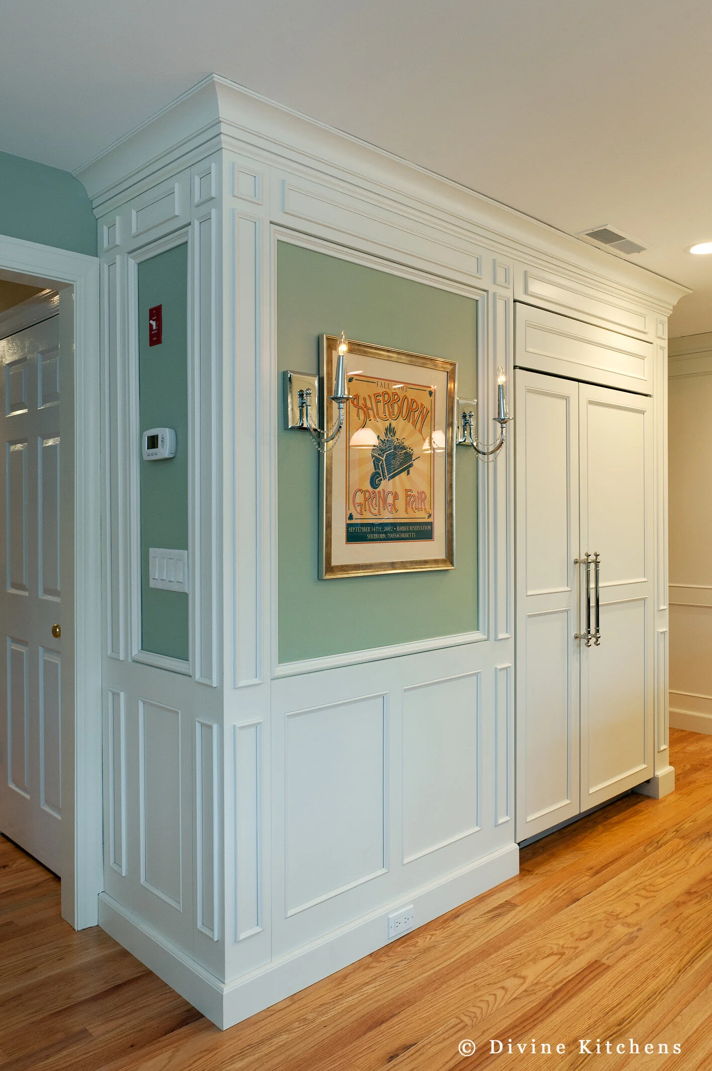 Traditional Kitchen with white shaker cabinetry and double decker appliances. Marble countertops float above a kitchen island and medium hardwood floors. A laundry room is adjacent to the kitchen.