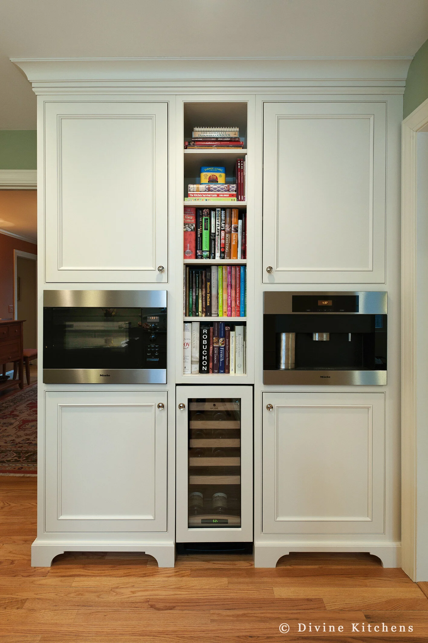 Traditional Kitchen with white shaker cabinetry and double decker appliances. Marble countertops float above a kitchen island and medium hardwood floors. A laundry room is adjacent to the kitchen.