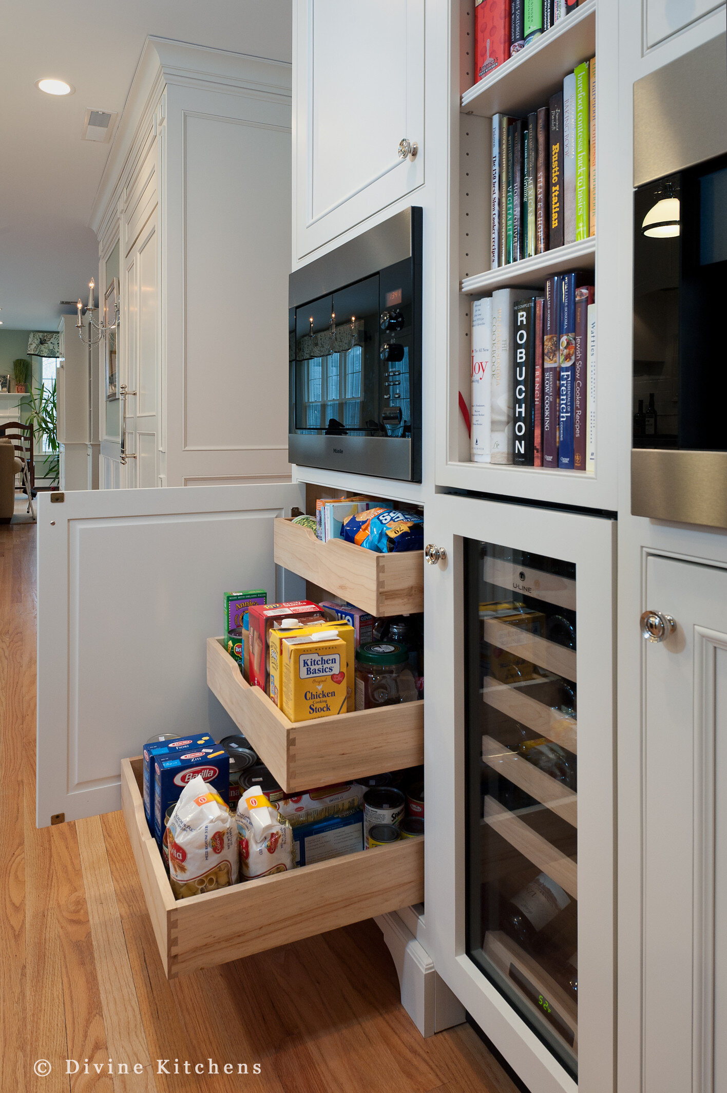 Traditional Kitchen with white shaker cabinetry and double decker appliances. Marble countertops float above a kitchen island and medium hardwood floors. A laundry room is adjacent to the kitchen.