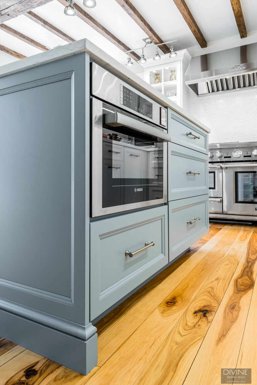 Blue traditional style kitchen island with cambria countertops and a bosch microwave integrated below the countertop