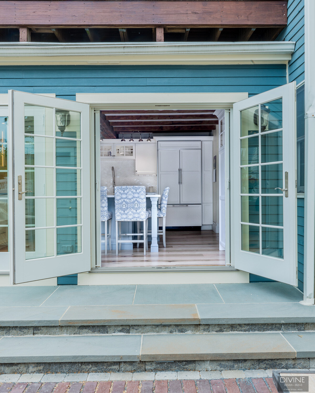 french doors that open from the kitchen and into the back yard. Blue, wood siding on exterior of house