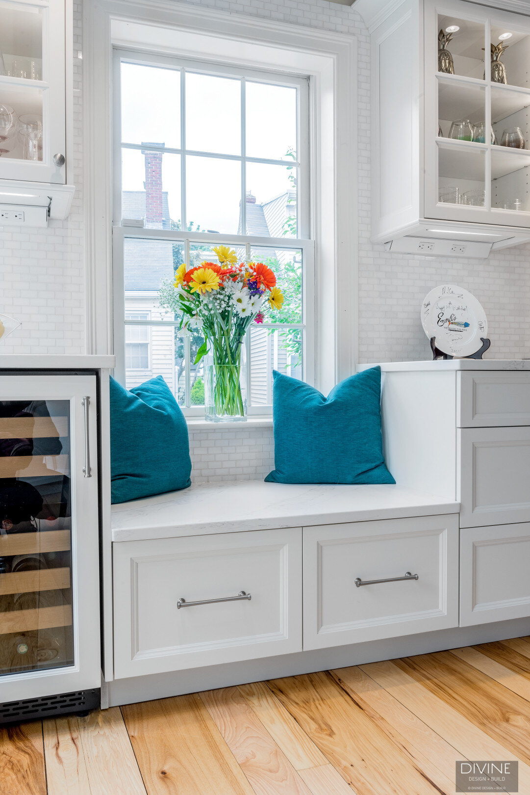 white, shaker style cabinets with brushed nickel accessories, wine fridge, and built-in bench seating below window with storage drawers