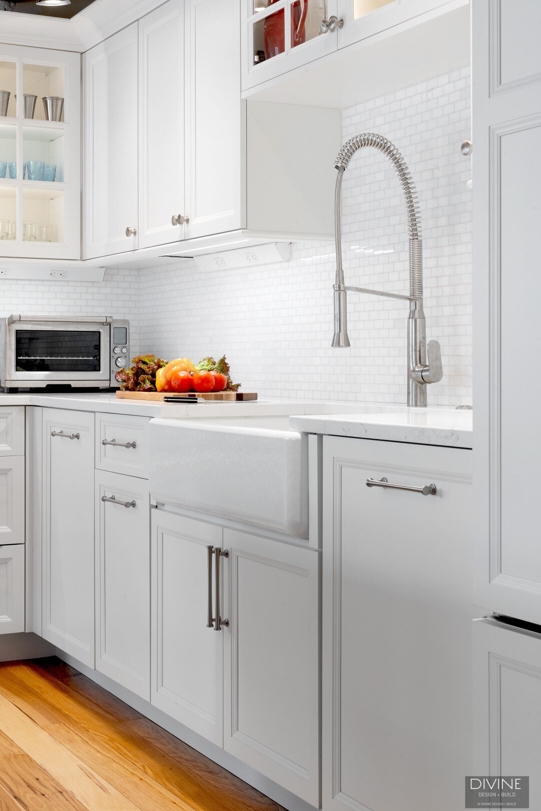 white, shaker style cabinets with brushed nickel accessories, white mosaic subway tile backsplash, cambria countertops with light marbling in grey tone and a paneled refrigerator