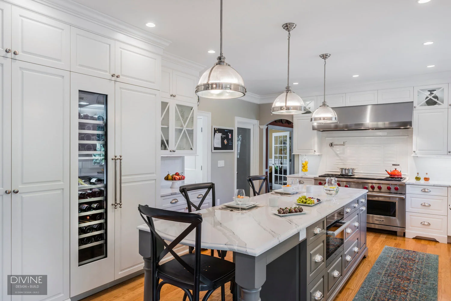  traditional shaker style kitchen. wolf appliances and chrome pendant lights. Calacatta countertops and medium hardwood floors. pull out pantry storage.