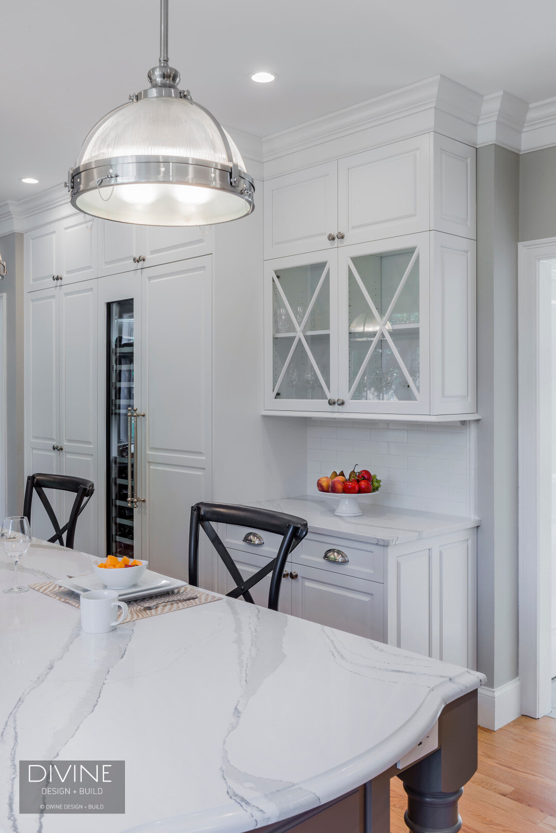  traditional shaker style kitchen. wolf appliances and chrome pendant lights. Calacatta countertops and medium hardwood floors. pull out pantry storage.