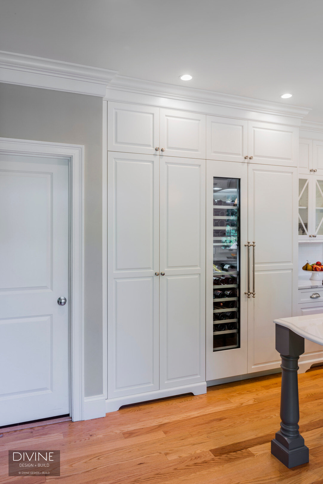  traditional shaker style kitchens with stainless steel farmhouse sink, wolf appliances and chrome pendant lights. Calacatta countertops and medium hardwood floors. Paneled refrigerator. 