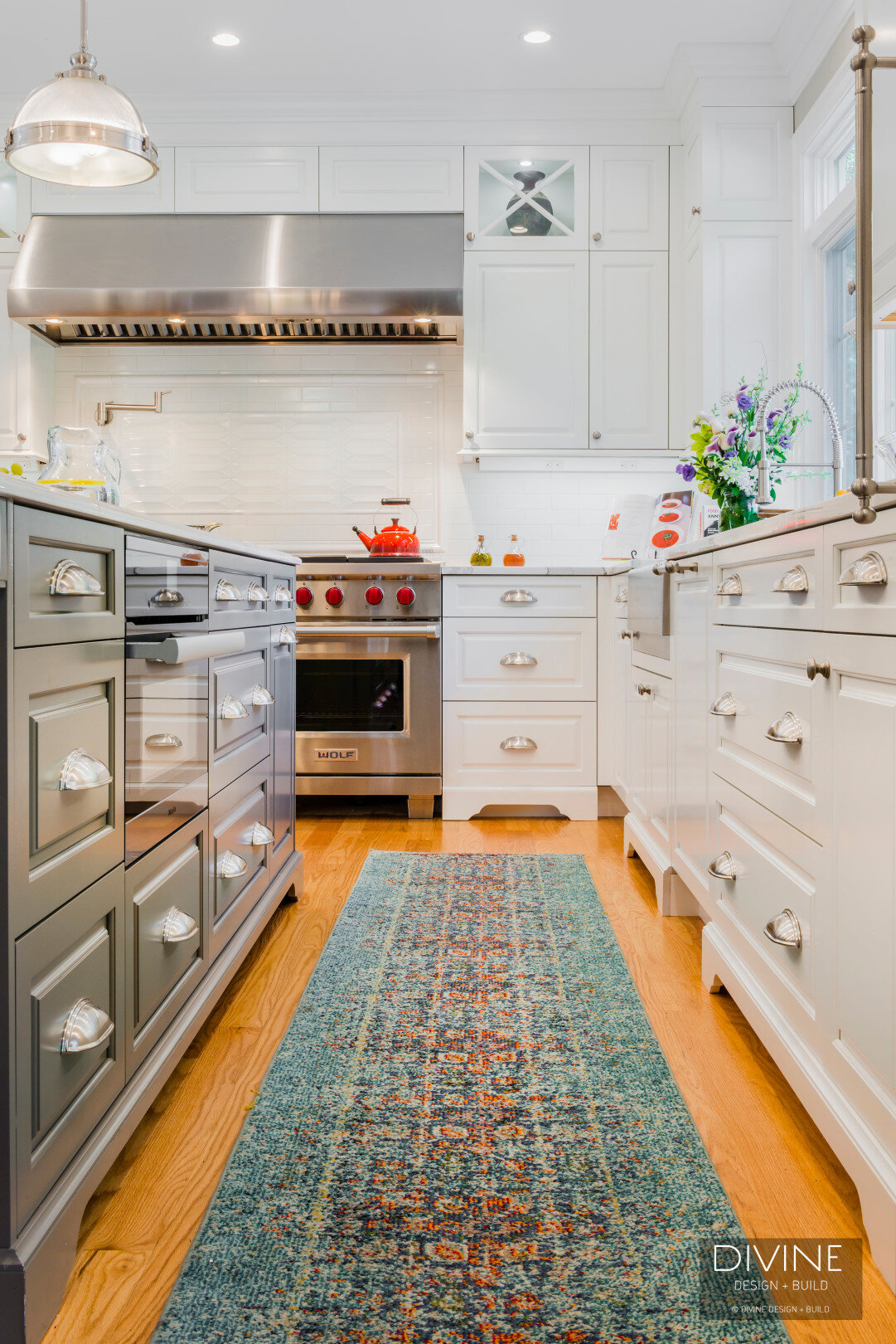 traditional shaker style kitchens with stainless steel farmhouse sink, wolf appliances and chrome pendant lights. Calacatta countertops and medium hardwood floors. Paneled refrigerator. 