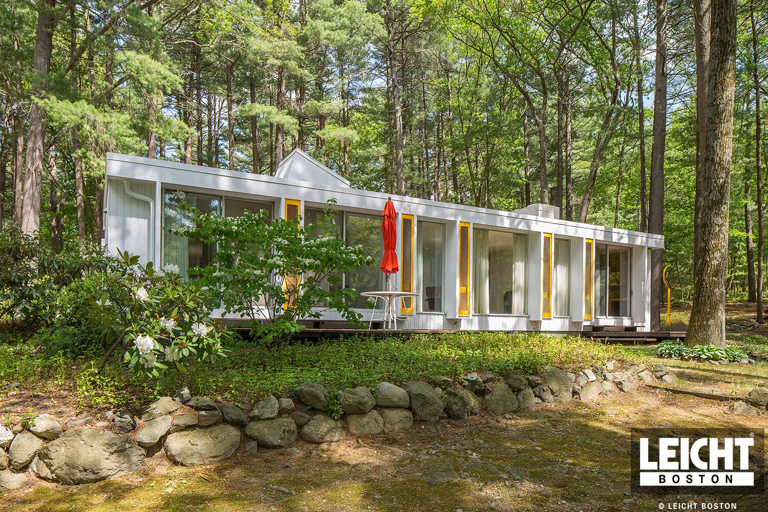 Historic home of famous architect earl flansburgh. Mid century modern style set in the deep woods. Floor to ceiling glass windows with yello accents and white stucco siding. 