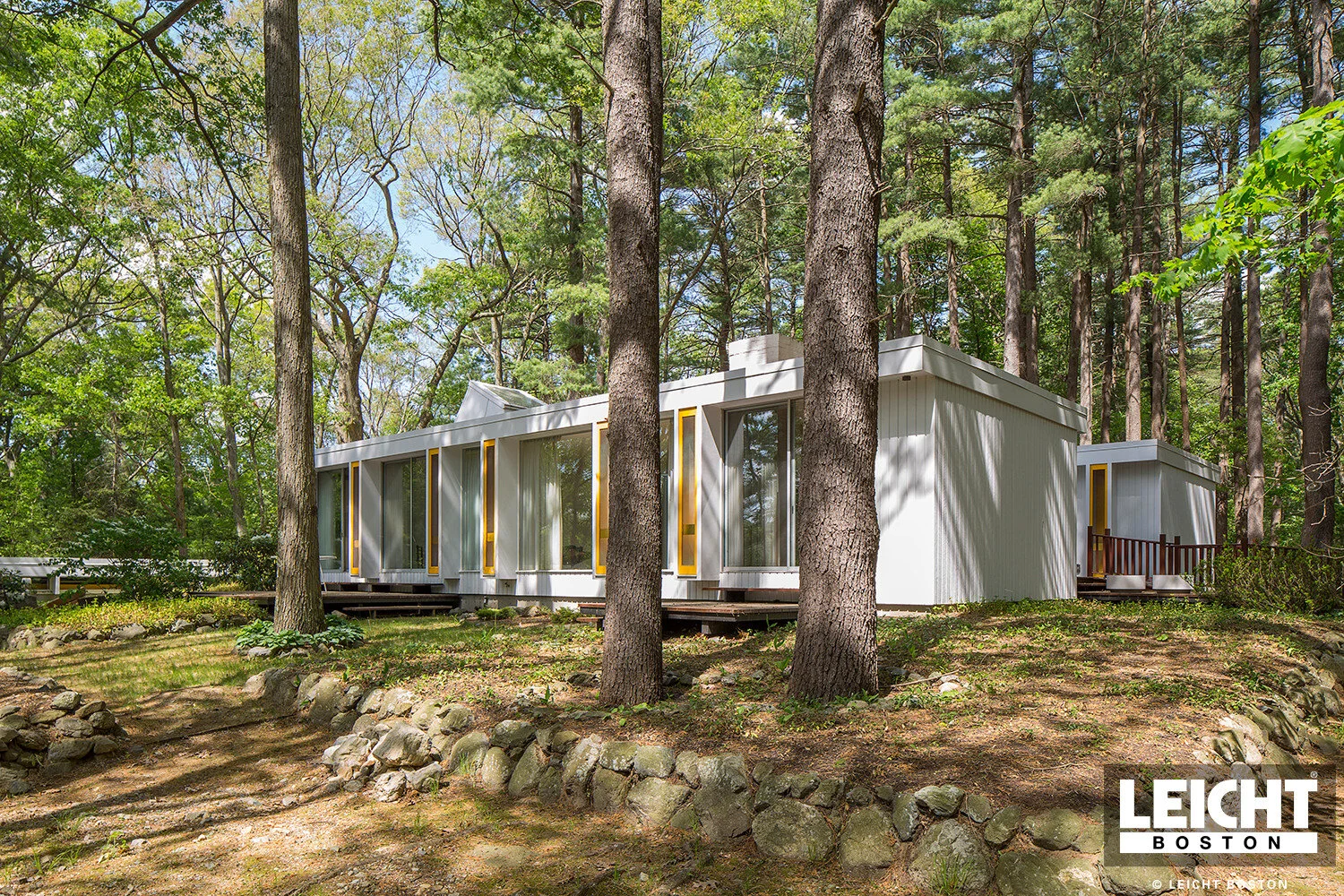 Historic home of famous architect earl flansburgh. Mid century modern style set in the deep woods. Floor to ceiling glass windows with yello accents and white stucco siding. 