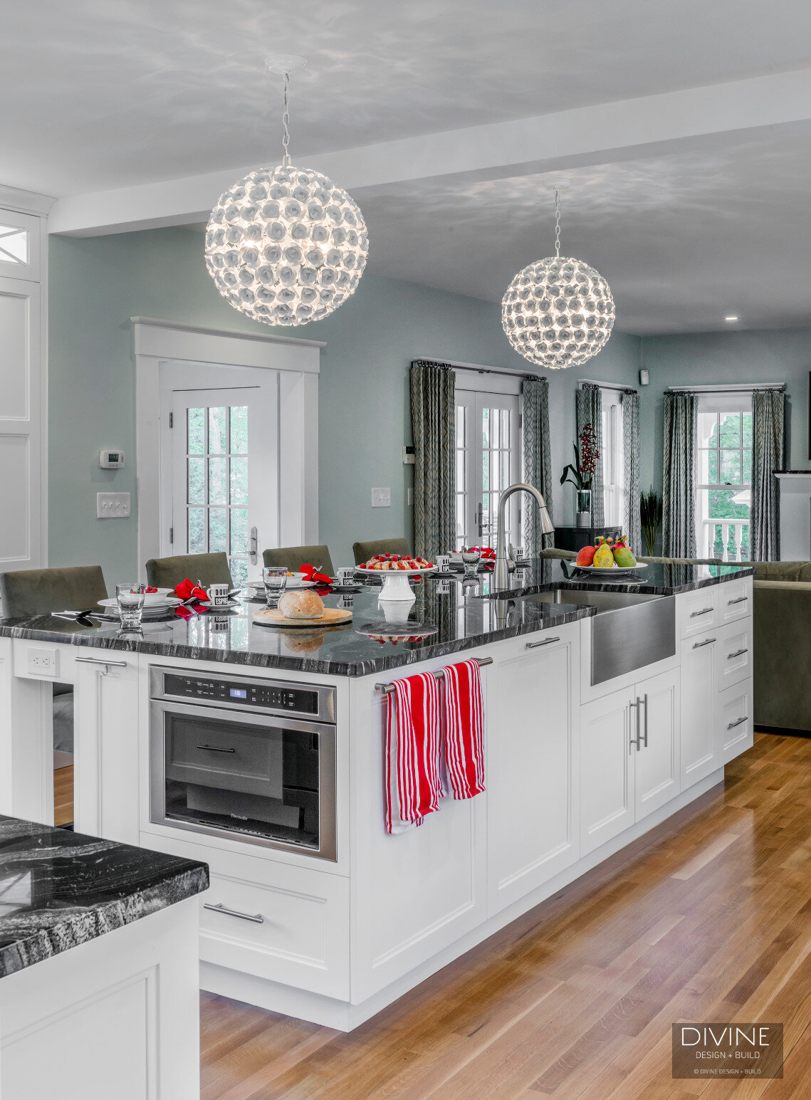  Floral sphere pendant lights with glass tiled back splash. Wolf appliances, stainless steel farmhouse sink. Granite countertops, and white shaker style cabinets.