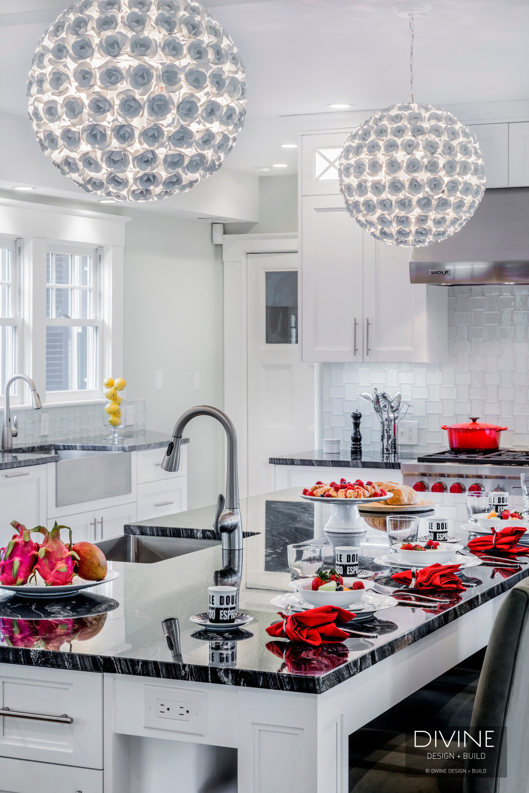  Floral sphere pendant lights with glass tiled back splash. Wolf appliances, stainless steel farmhouse sink. Granite countertops, and white shaker style cabinets.