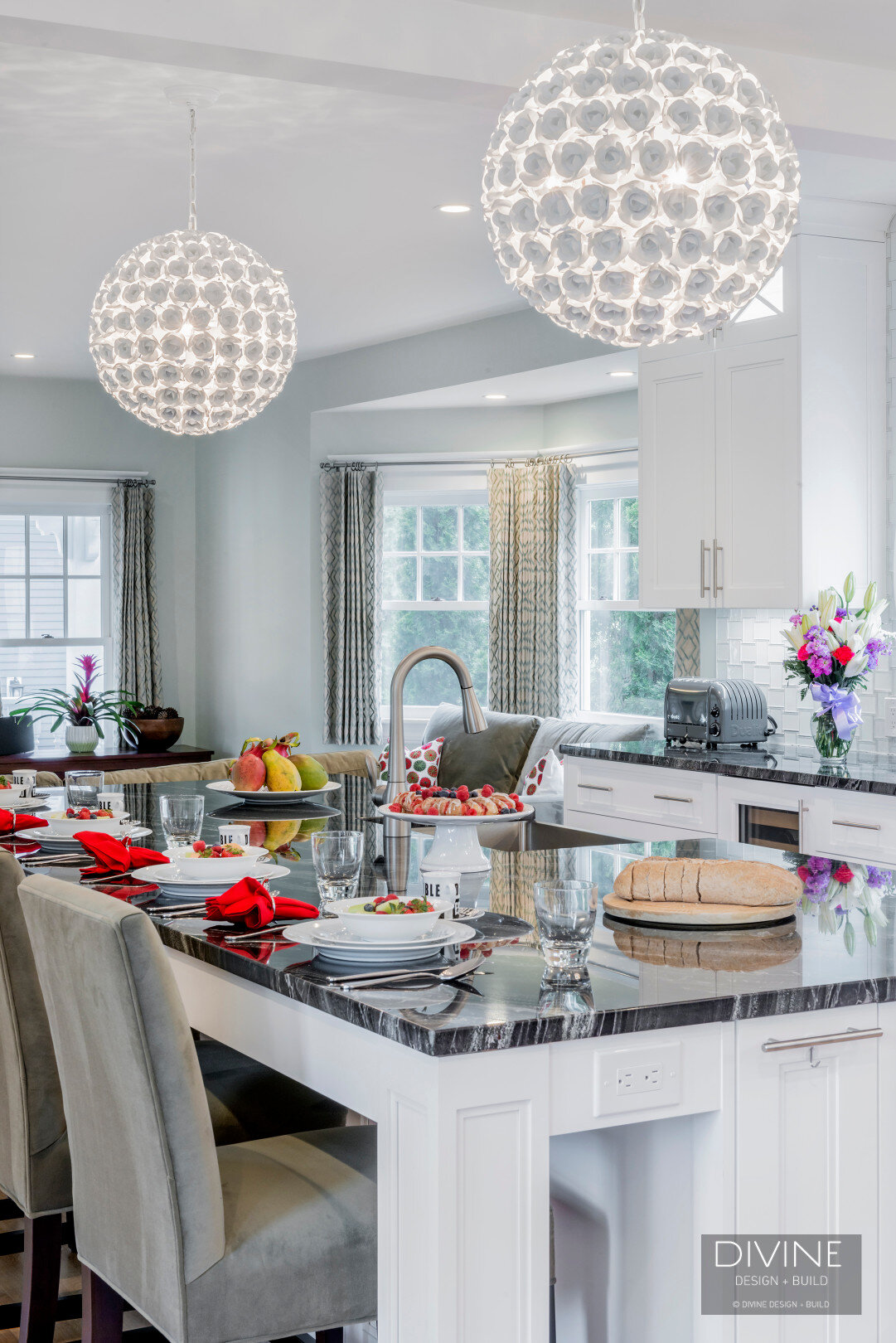  Floral sphere pendant lights with glass tiled back splash. Wolf appliances, stainless steel farmhouse sink. Granite countertops, and white shaker style cabinets.